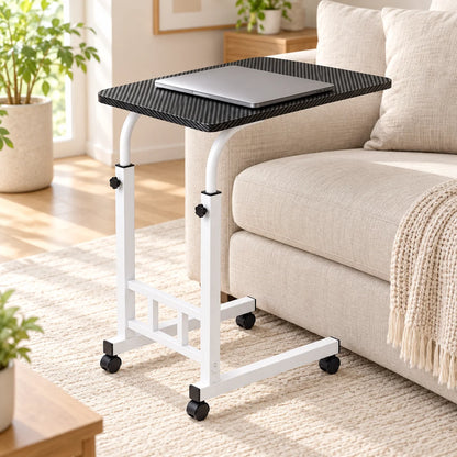 Adjustable rolling side table beside a light sofa with a closed laptop